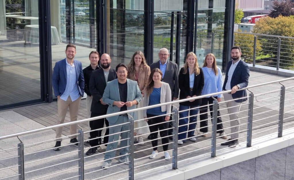 Campus-EW Team vor modernem Gebäude Gruppenfoto des Campus-EW Teams vor einem modernen Glasgebäude.